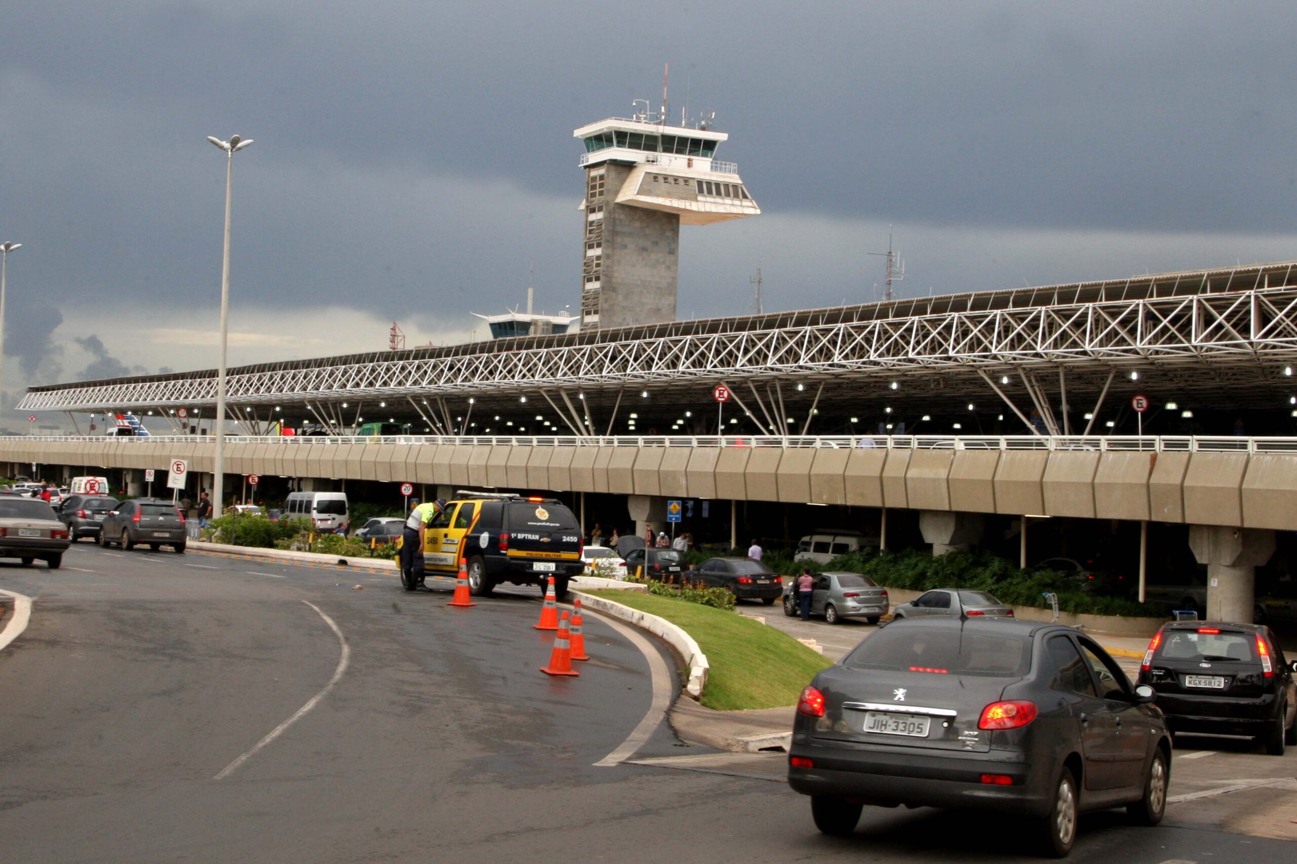 Faxada do aeroporto do Distrito Federal com carros entrando na área de embarque e desembarque