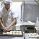 Padeiro produz pequenos pães na cozinha da padaria (matéria sobre MEI)