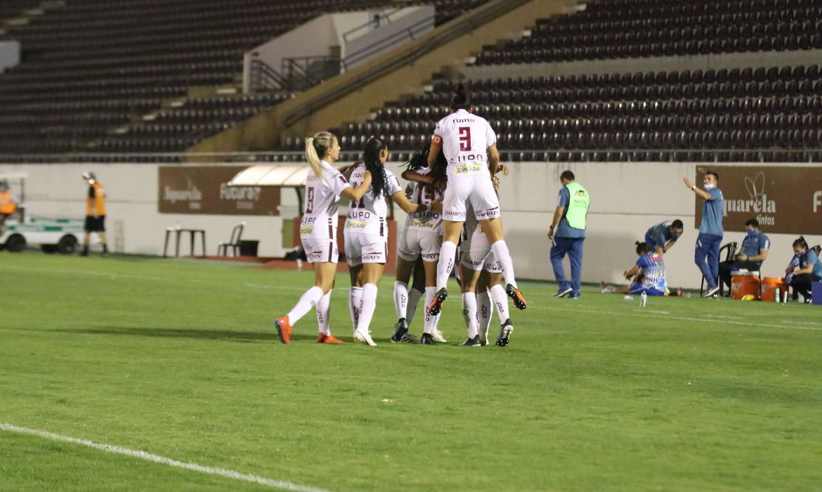 Jogadoras comemoram em campo de futebol